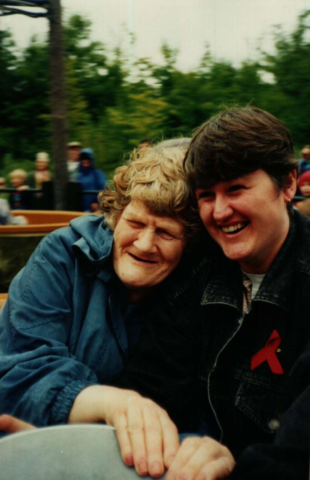 Two women sit close together on a fairground ride laughing