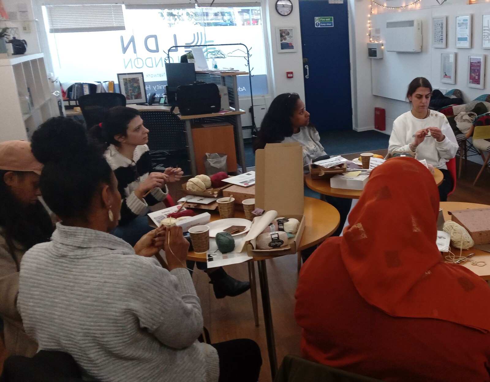A group of people knitting and listening to a speaker