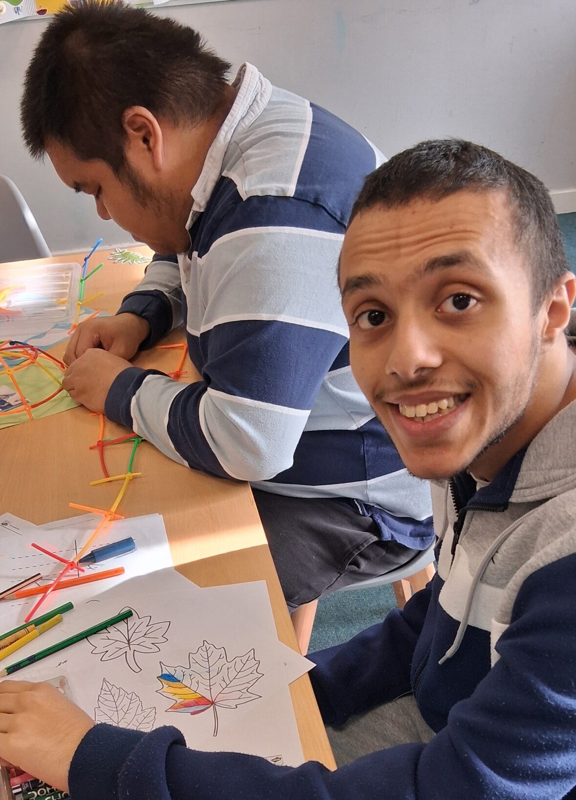 two young people sitting at a table one person facing the camera