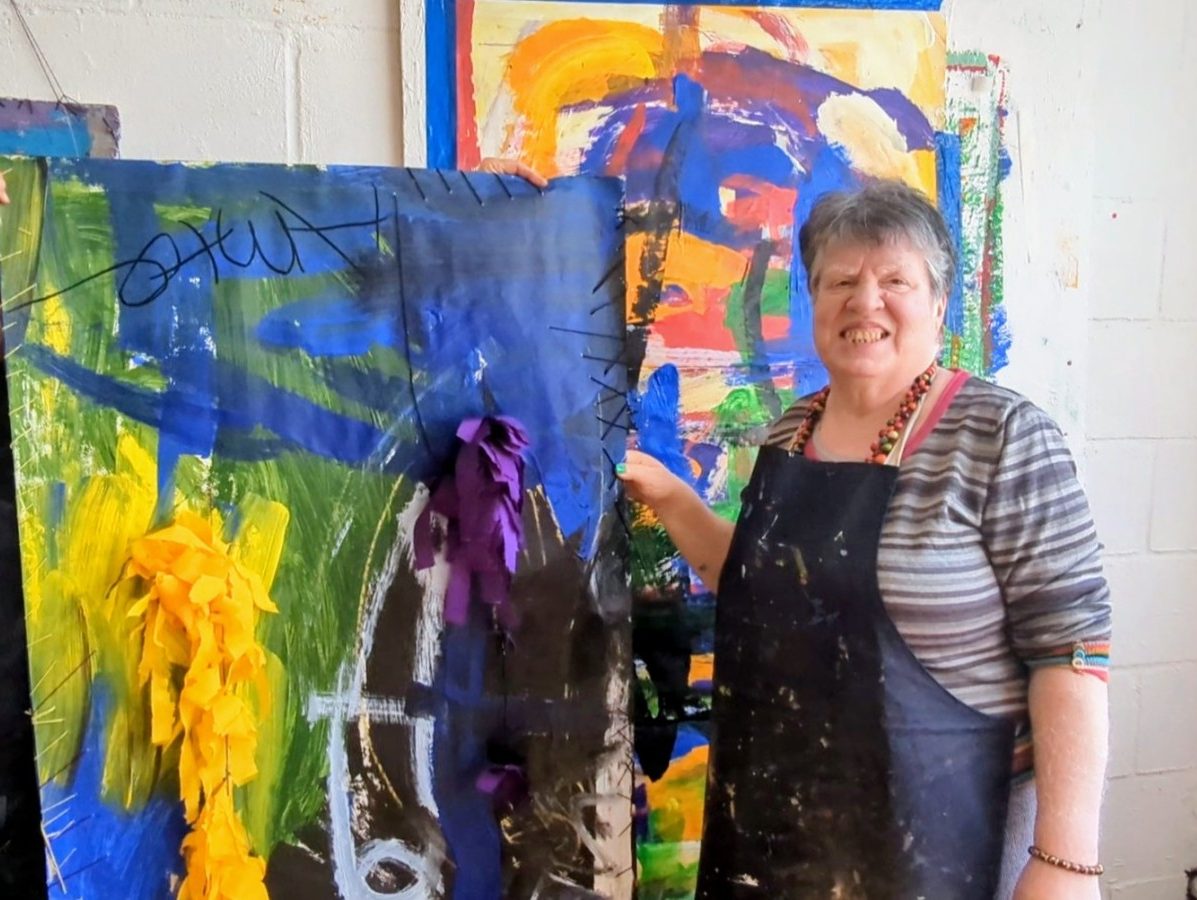 A woman standing by a colourful canvas