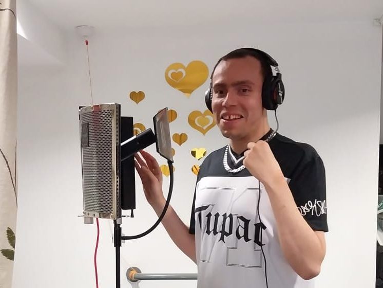 Man wearing headphones recording into a microphone in a studio