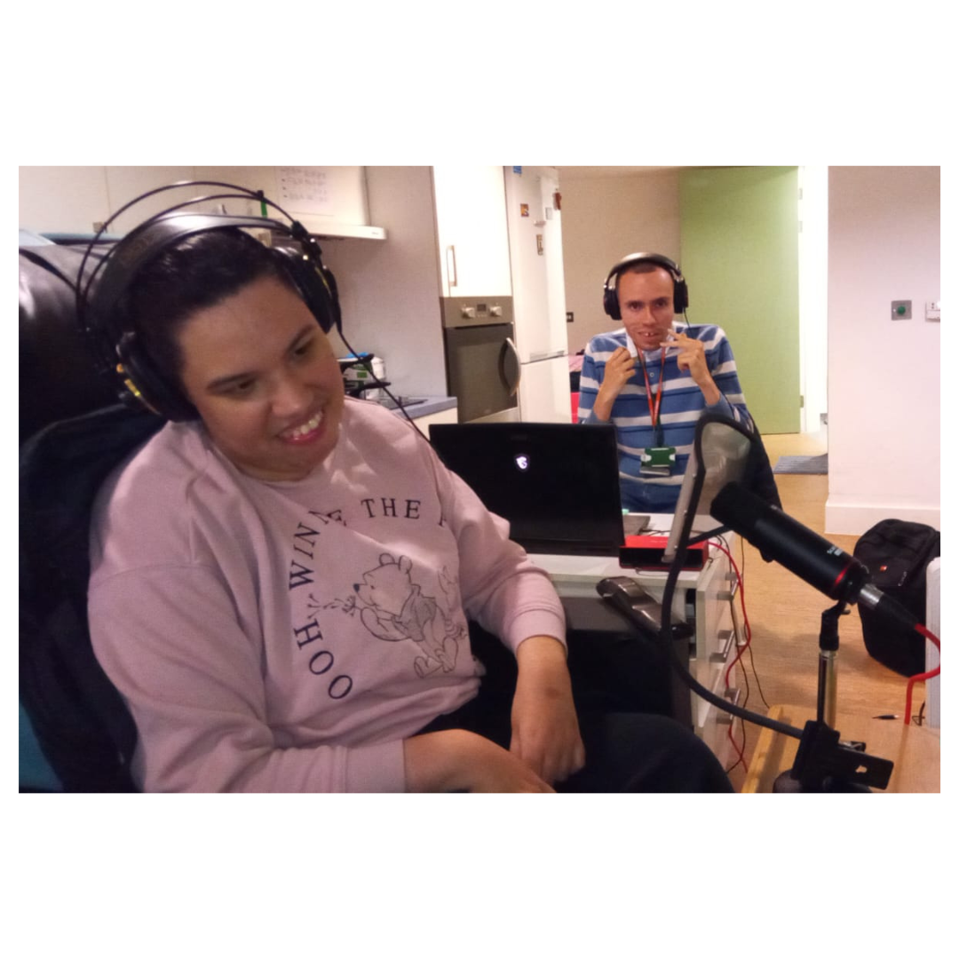 Two people wearing headphones sitting with a microphone
