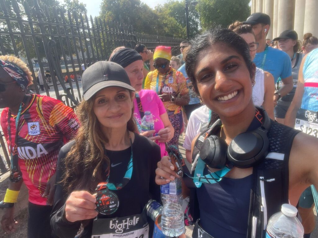 Two runners smiling and holding finisher medals after the Big Half race.