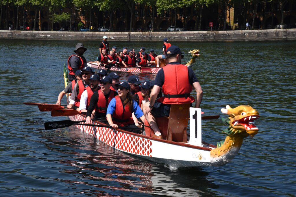 Two teams paddling a dragon boat during a race on a river.