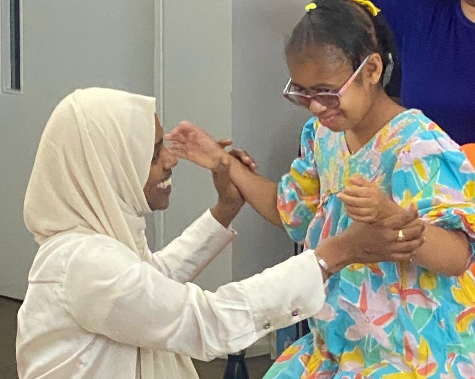 Adult supporting a child while they play and interact indoors.