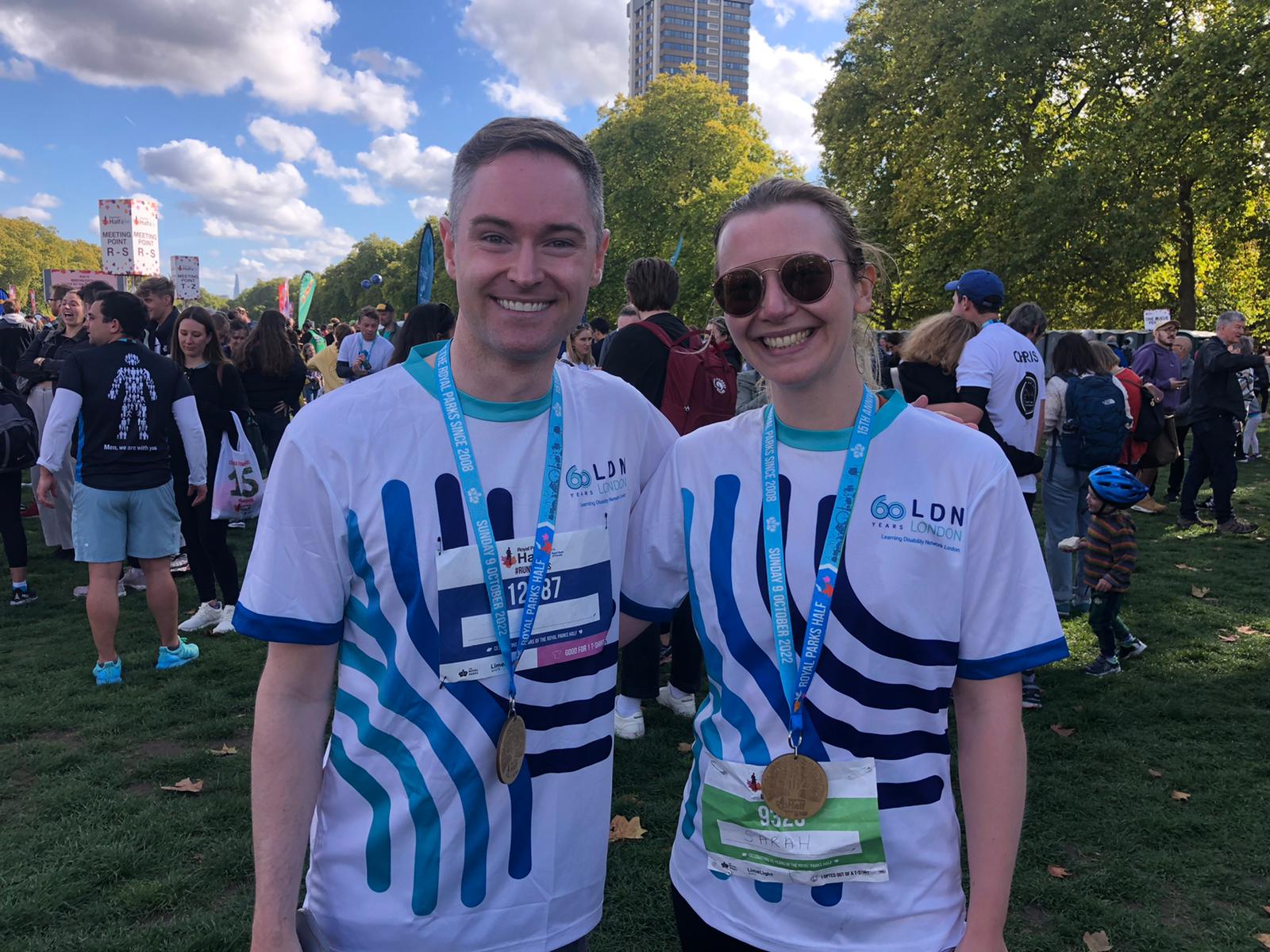 Two runners wearing medals smiling after completing a race.