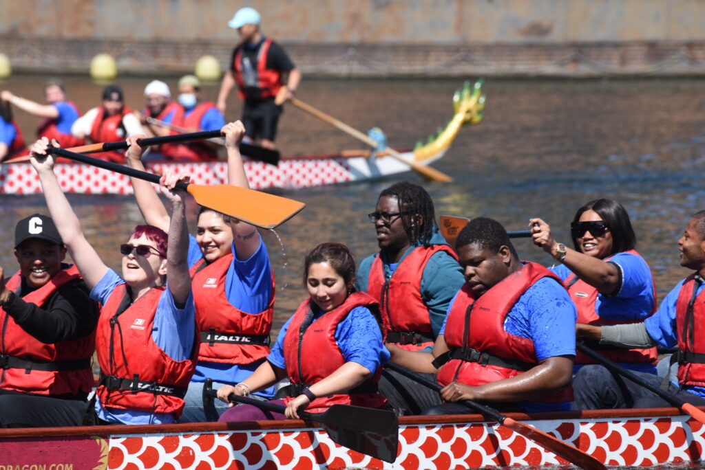 People paddling a dragon boat during a fundraising event.