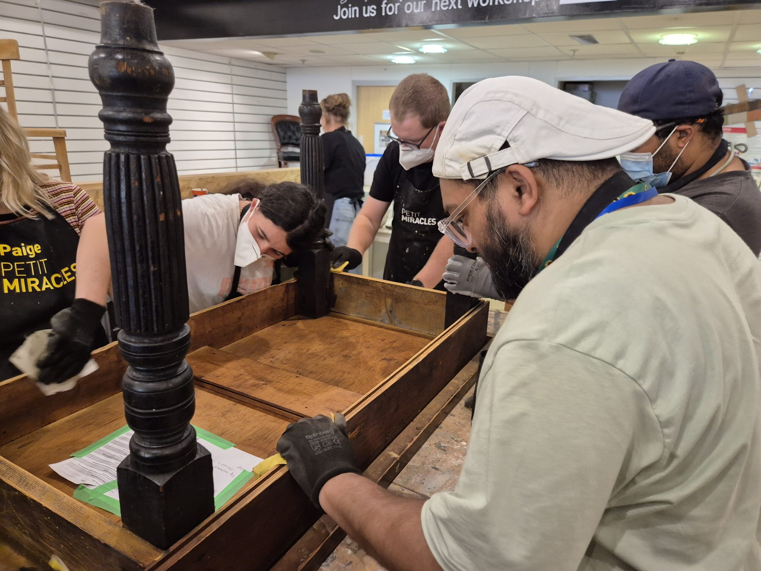 People working together restoring furniture at a workshop table.
