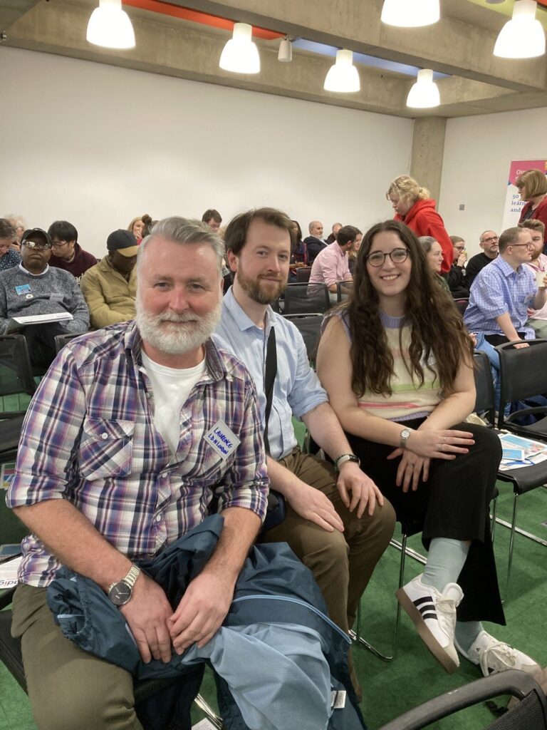 Three people sitting together at a community meeting workshop.