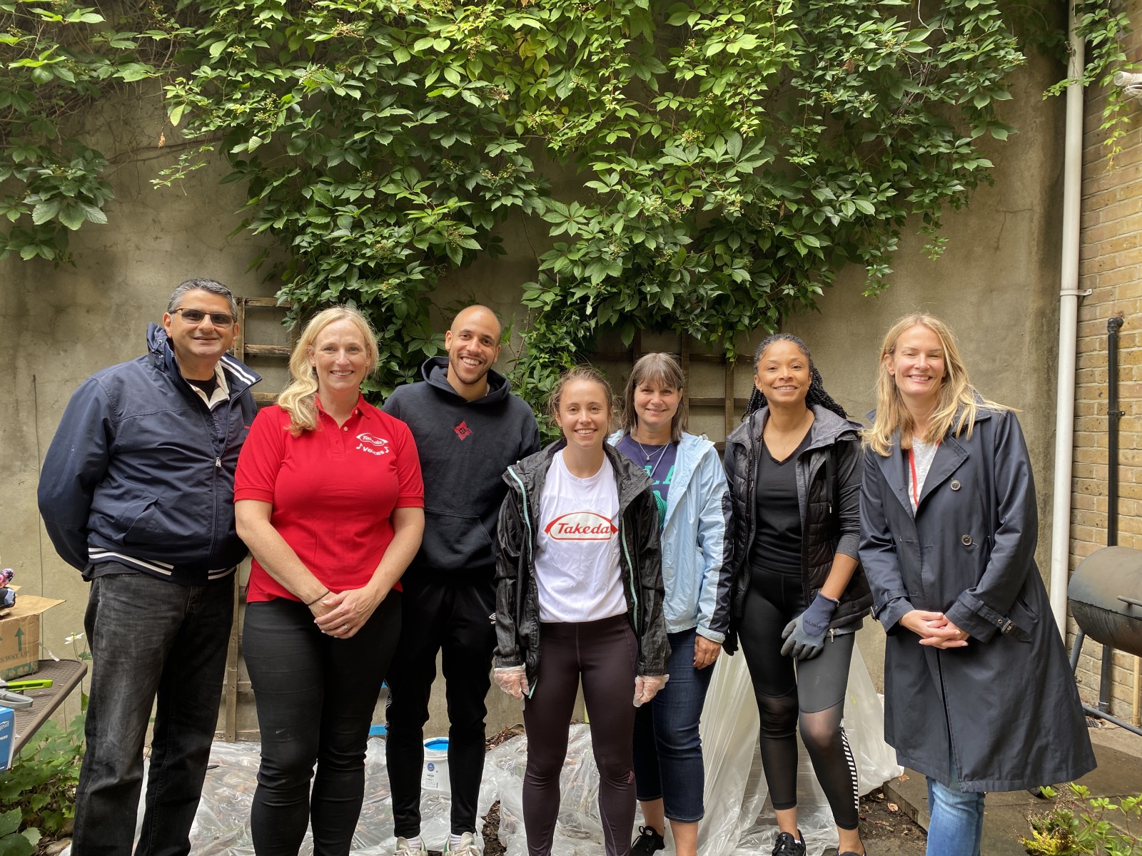 A group of staff from Takeda stand in a garden smiling