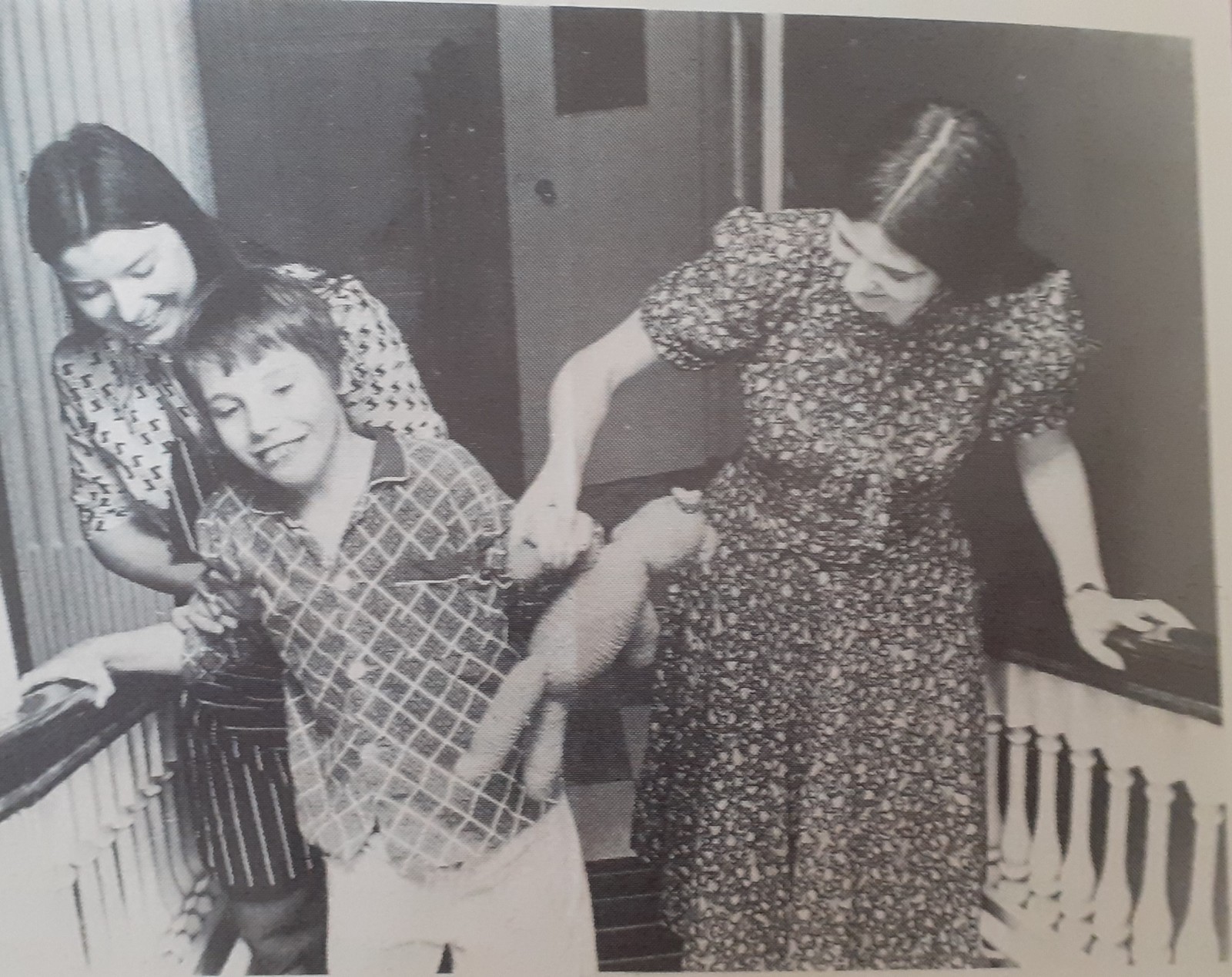 Two women help a child walk upstairs