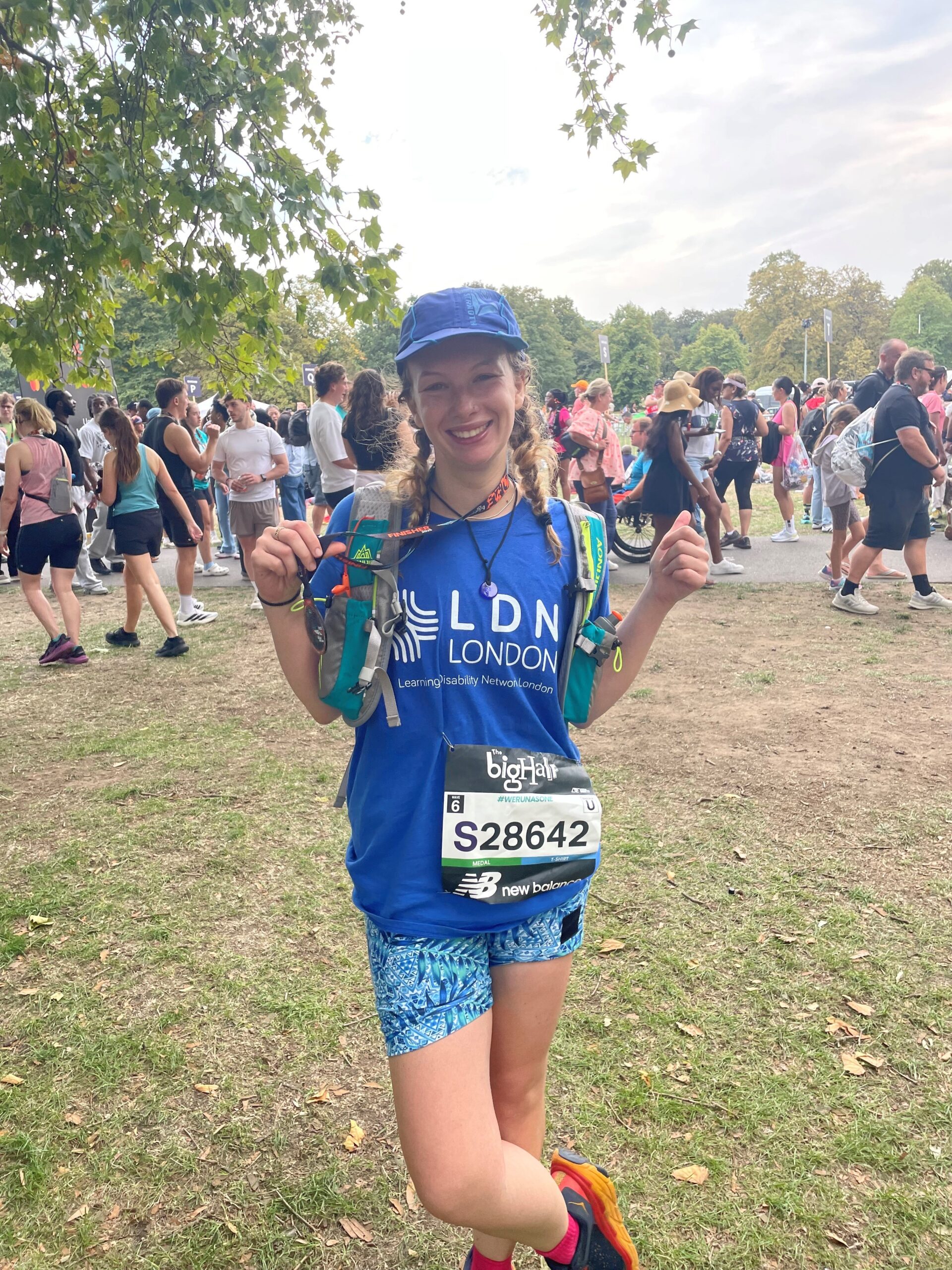 Person in blue LDN London T-shirt holiding up medal after running in the Big Half marathon