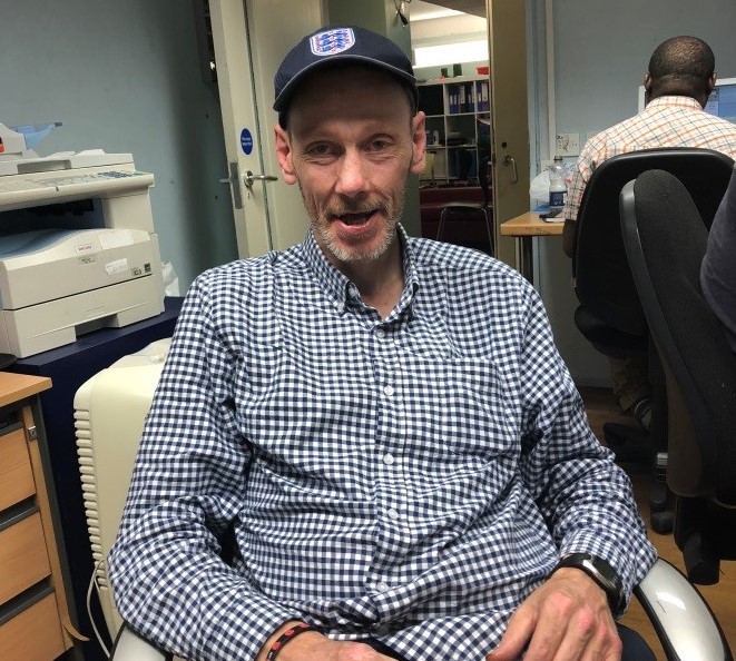 A man in a chair looks at the camera