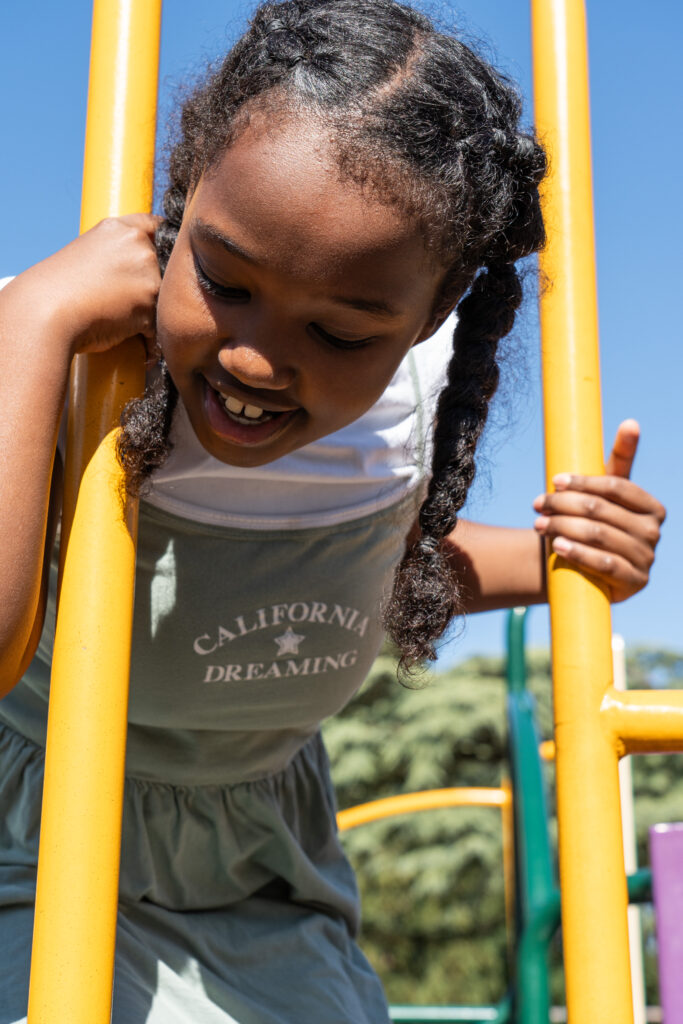 Young girl playing on climbing equipment at a playground.