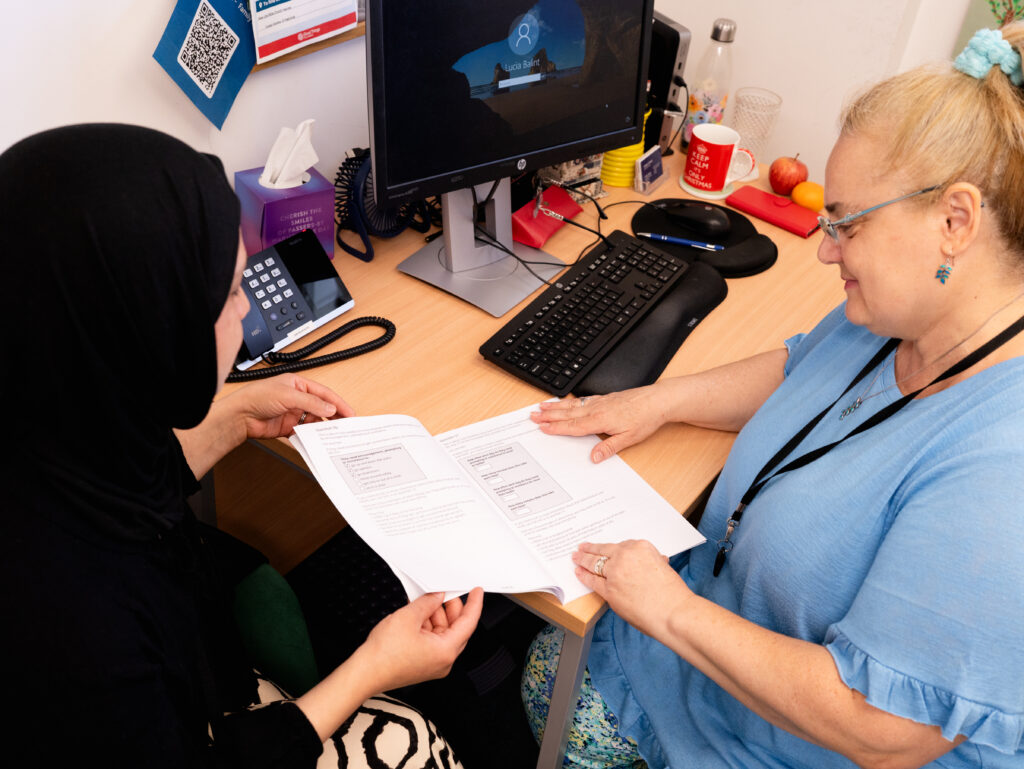 Family worker and parent together at a desk reviewing documents.
