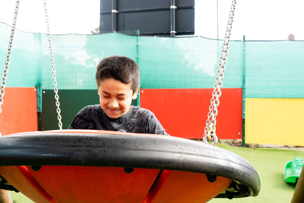 A young boy on a swing in the garden at CKA