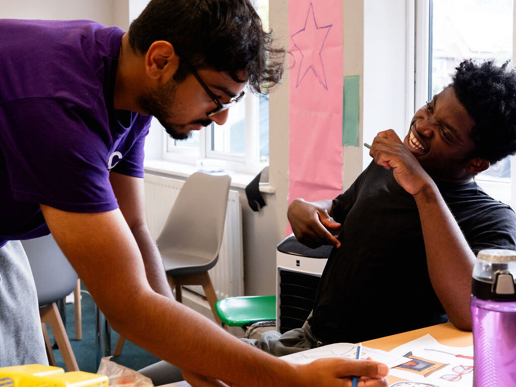 A young person and support worker interacting and laughing