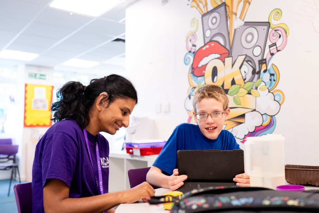 Young person and support worker playing on a tablet together