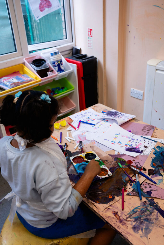 A young girl painting and getting very messy