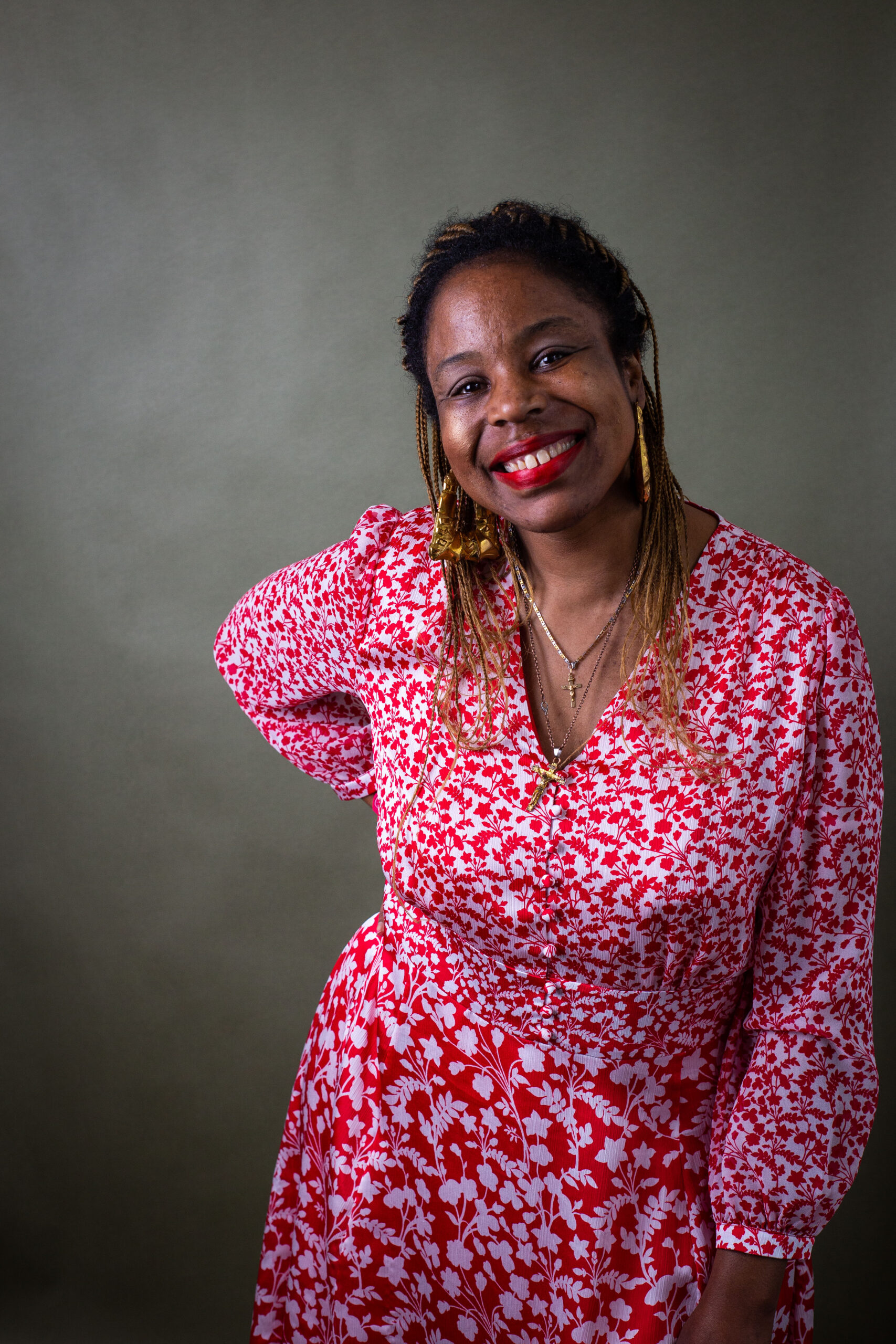 Woman smiling in a portrait wearing a red patterned dress.