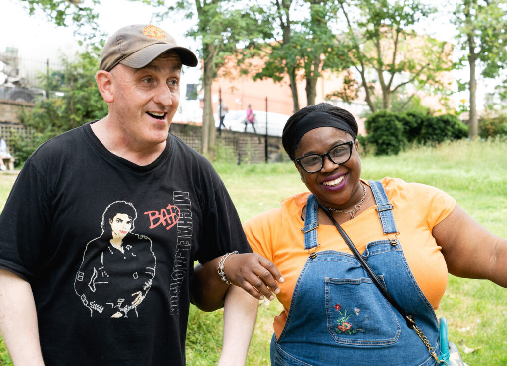 Two people outside in a park laughting and linking arms