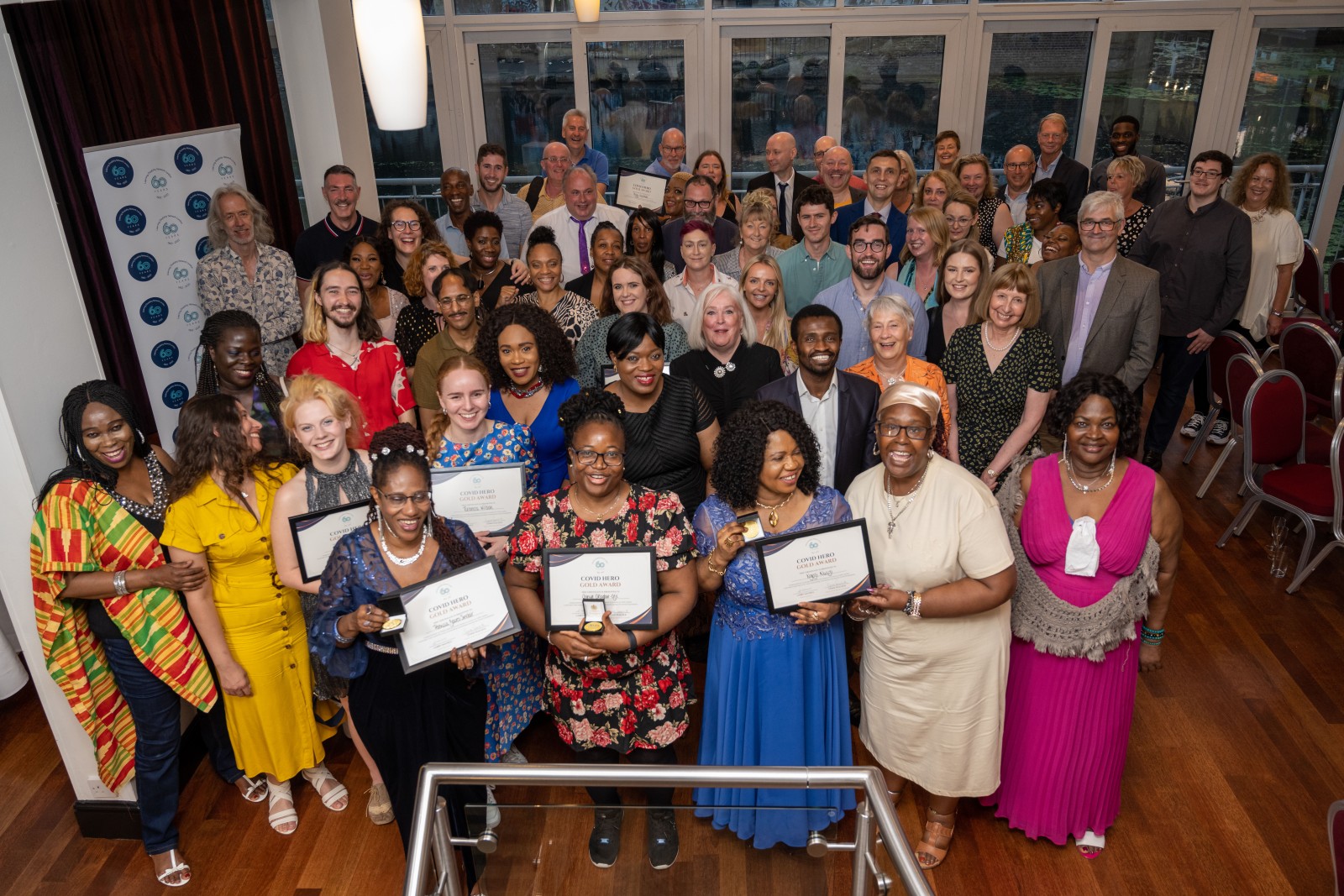 A group of people holding certificates smile up at the camera