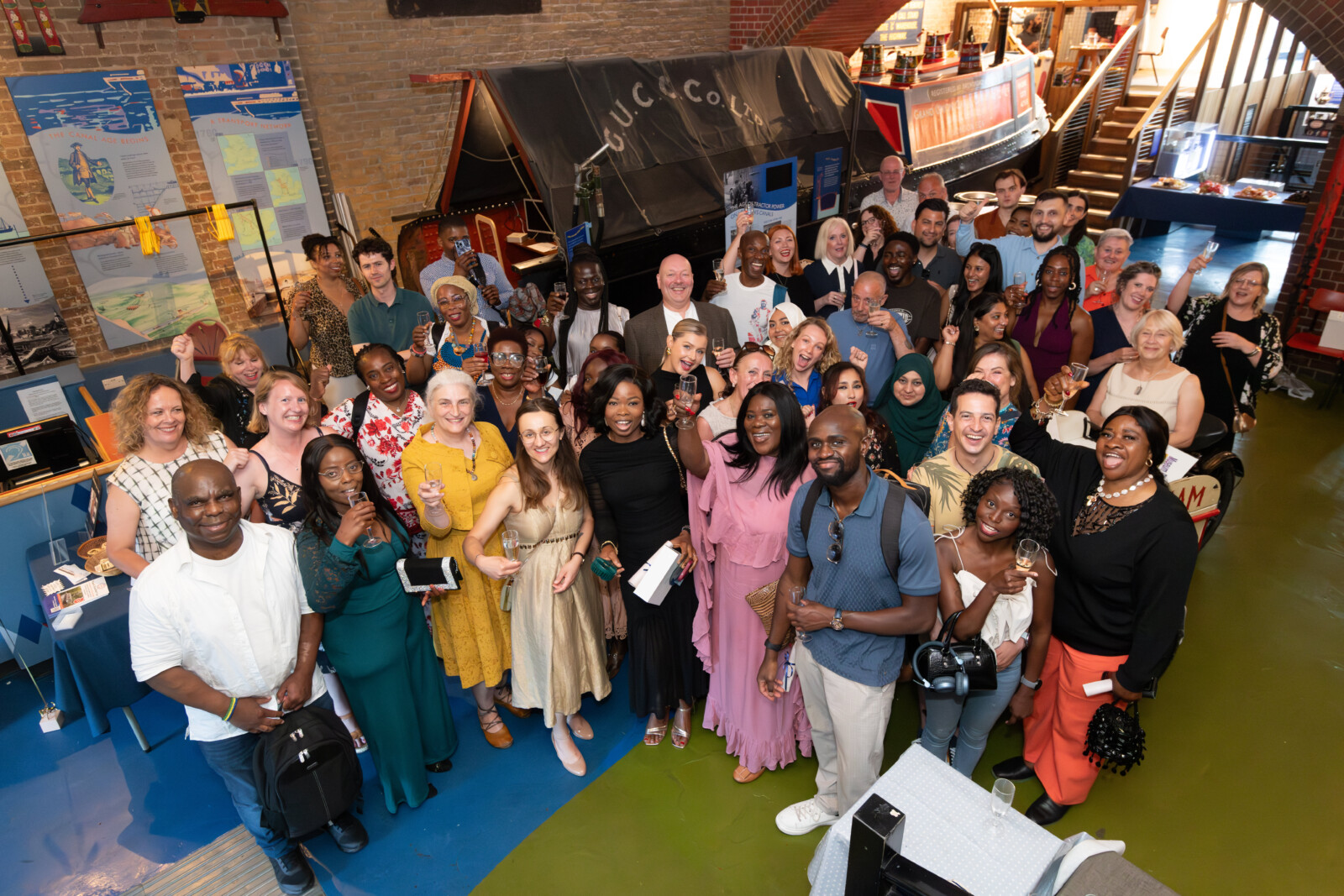 A large group of people smiling and holding up their glasses