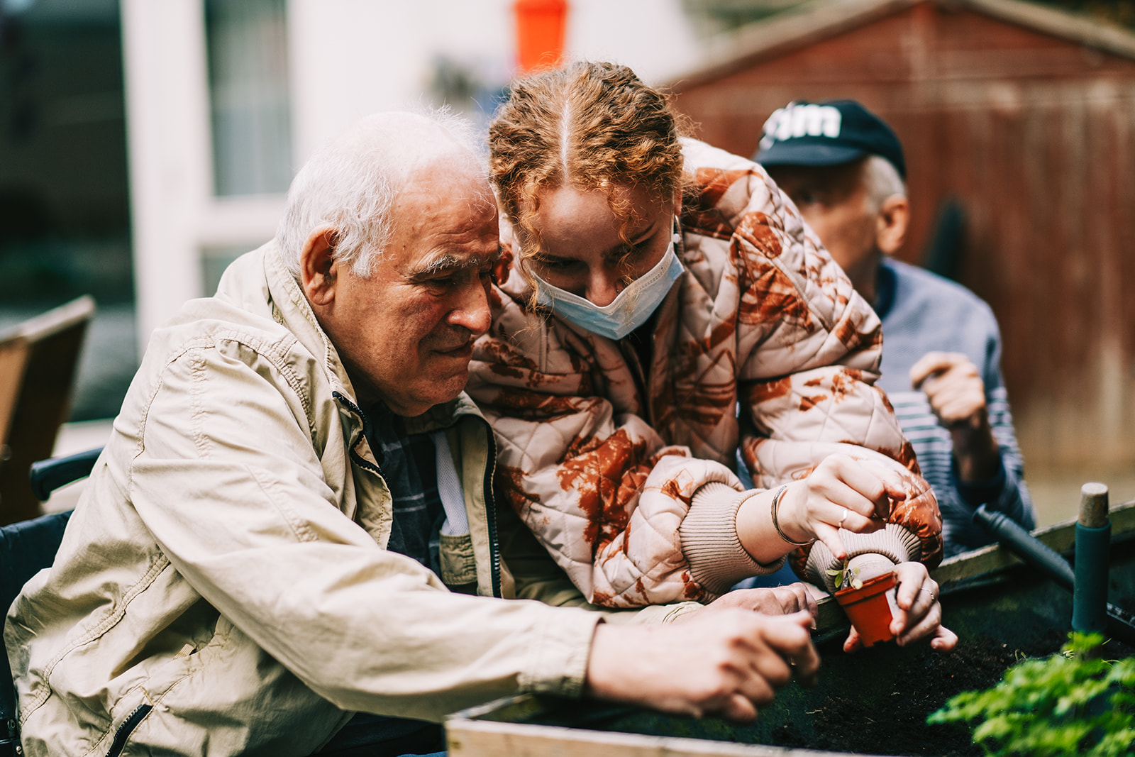 A woman and a man are planting seedlings in a raised bed