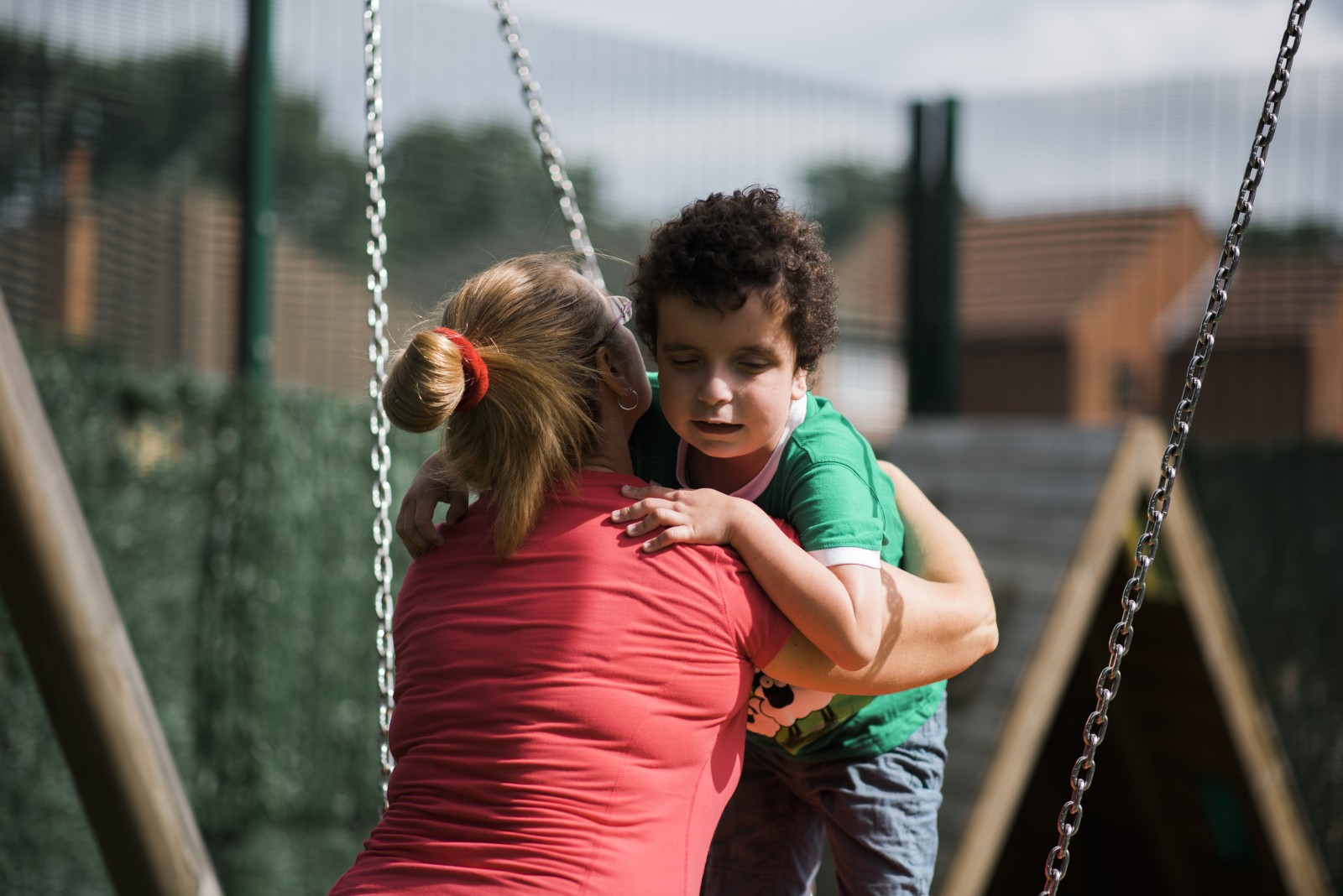 A woman helps a child on a swing