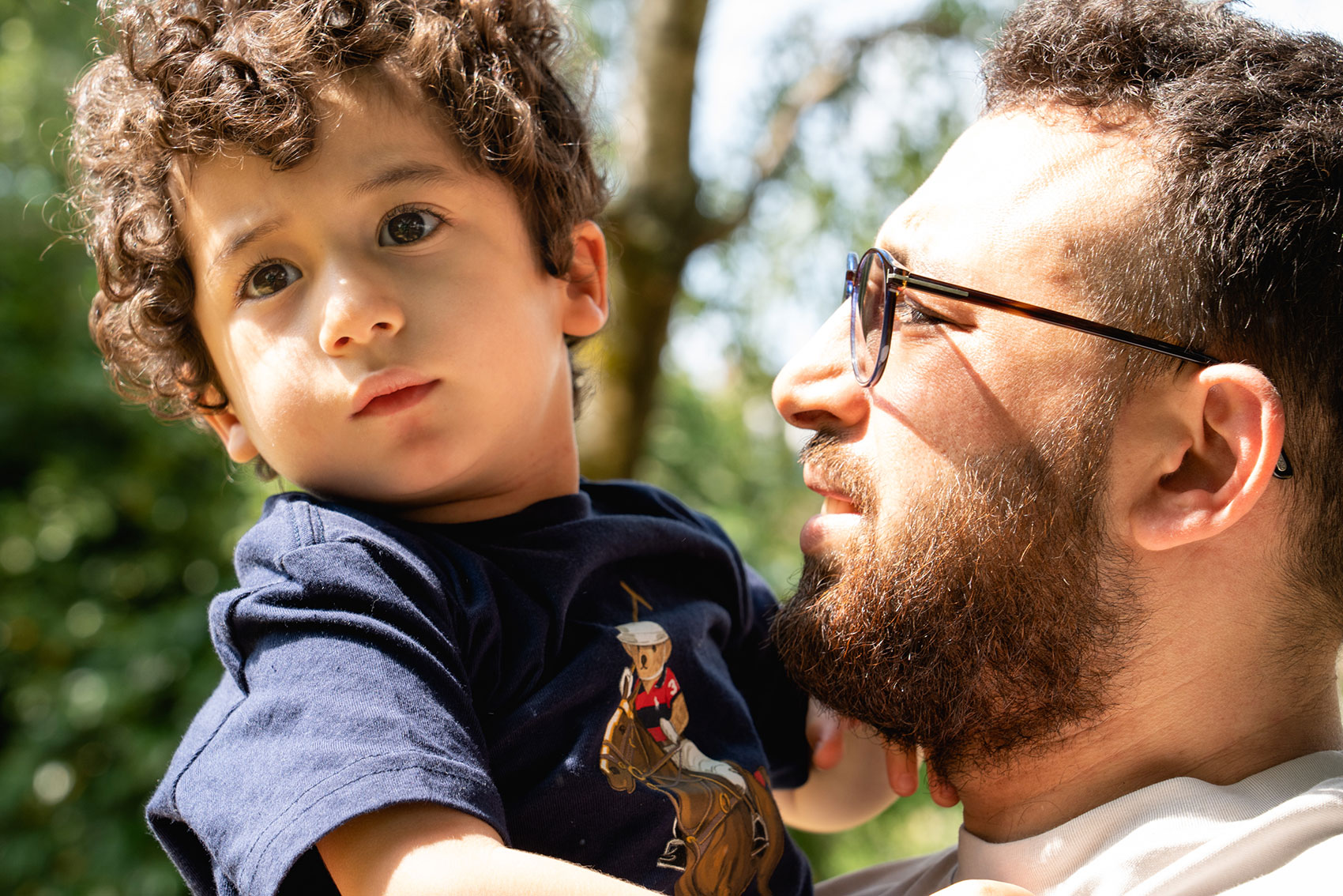 Adult and child smiling together outdoors while spending time together.