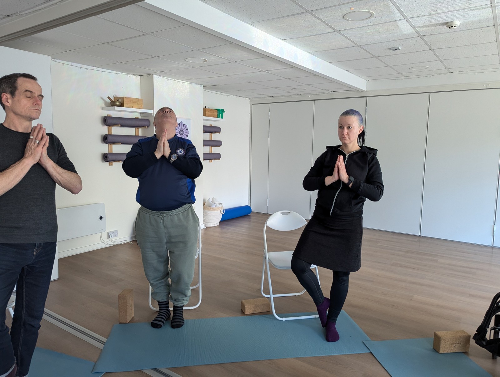 Three people standing with their hands together balancing