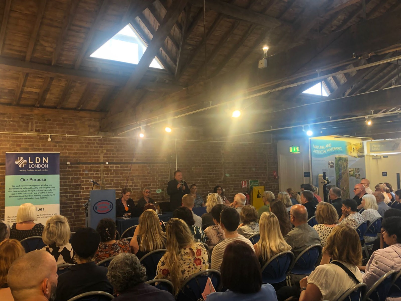A group of people looking at a panel where a man is speaking on the microphone