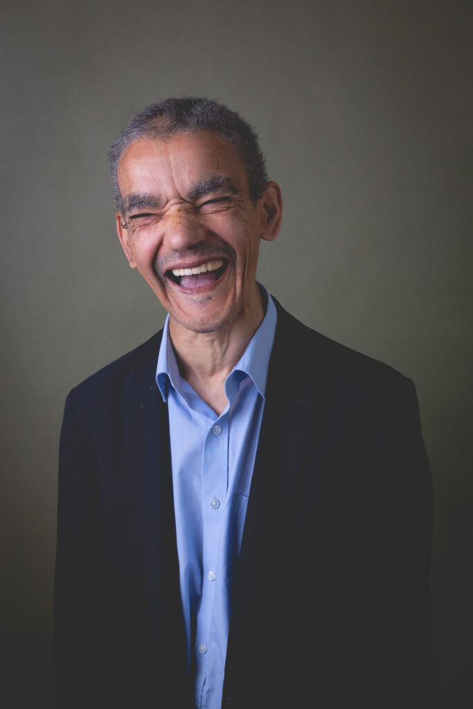 Man smiling in a studio portrait wearing a shirt and blazer.