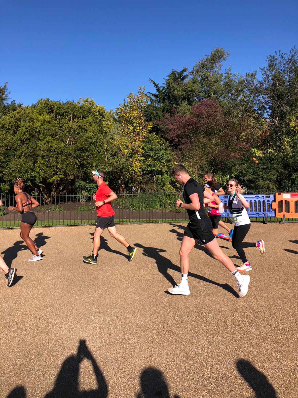 Group of runners in a race with one runner smileing and waving wearing and LDN London running top