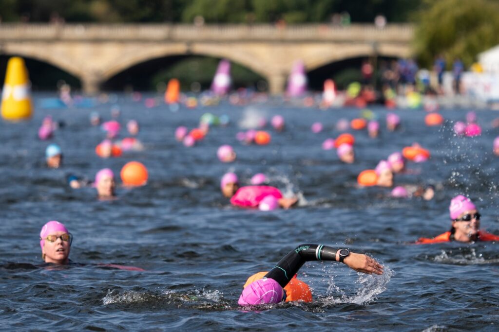 Swimmers wearing brightly coloured caps taking part in an open water swim event.