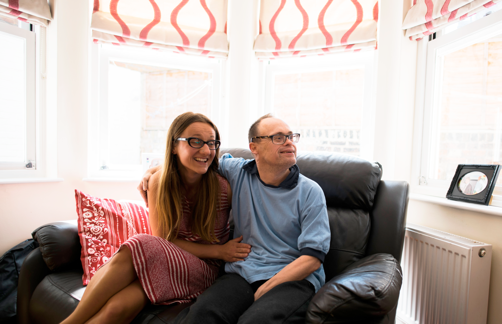 Two people sitting on a sofa in a window smiling