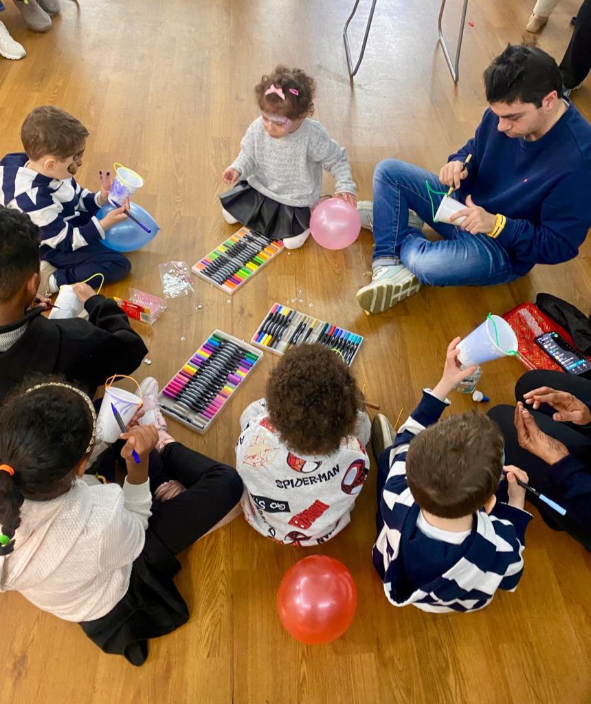 Group of children and adults sitting in a circle do arts and crafts