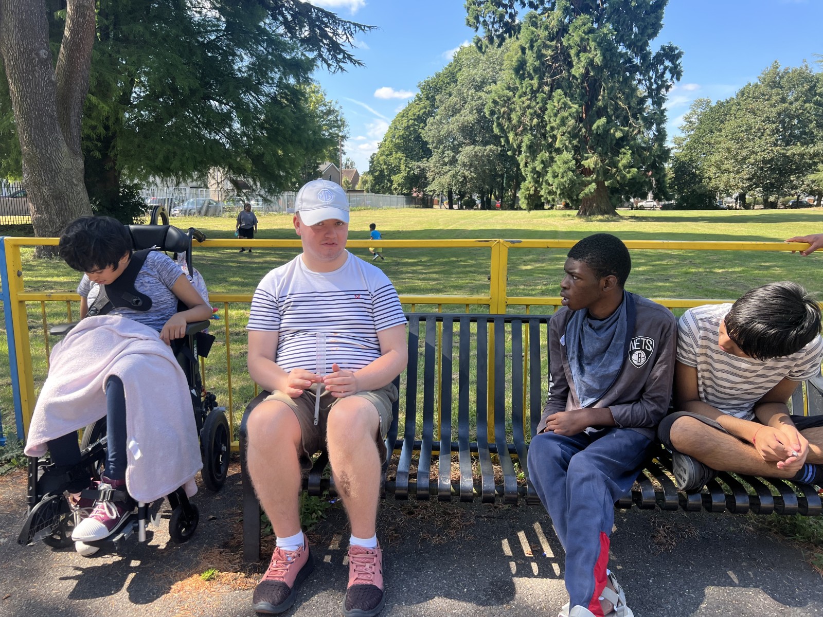 A group of young people sitting on a bench in a park