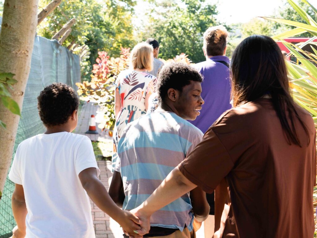 People walking together along a garden path, with one person holding hands for support.